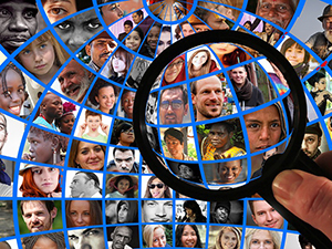 Magnifying glass focused on globe made of individual people's faces